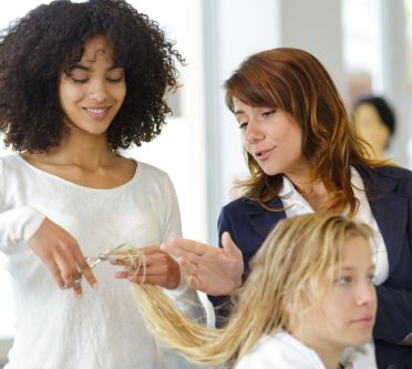 trainee hairdresser cutting clients hair